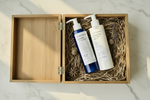 Two skincare products in a wooden box on a marble surface