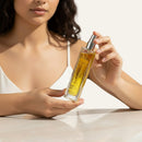 Woman holding a bottle Body_moisturizing_blend_of_precious_oils_with_vitamin_E