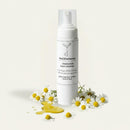White bottle with Skincare of theOliveSense Cleaning Foam with Chamomile & vitamin E soap  on a decorative white and yellow flower pattern 