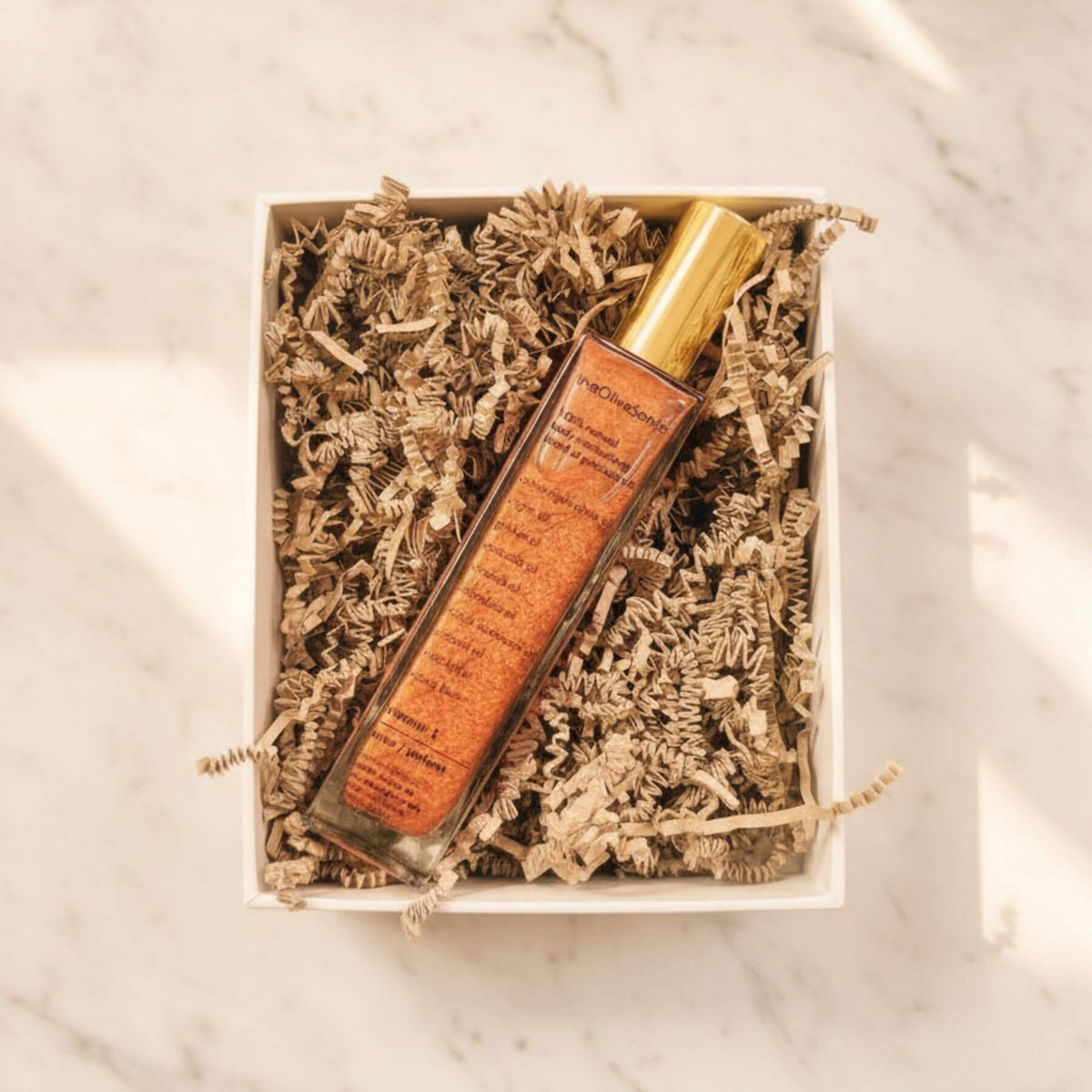 Lip balm in a decorative box with shredded paper on a marble surface