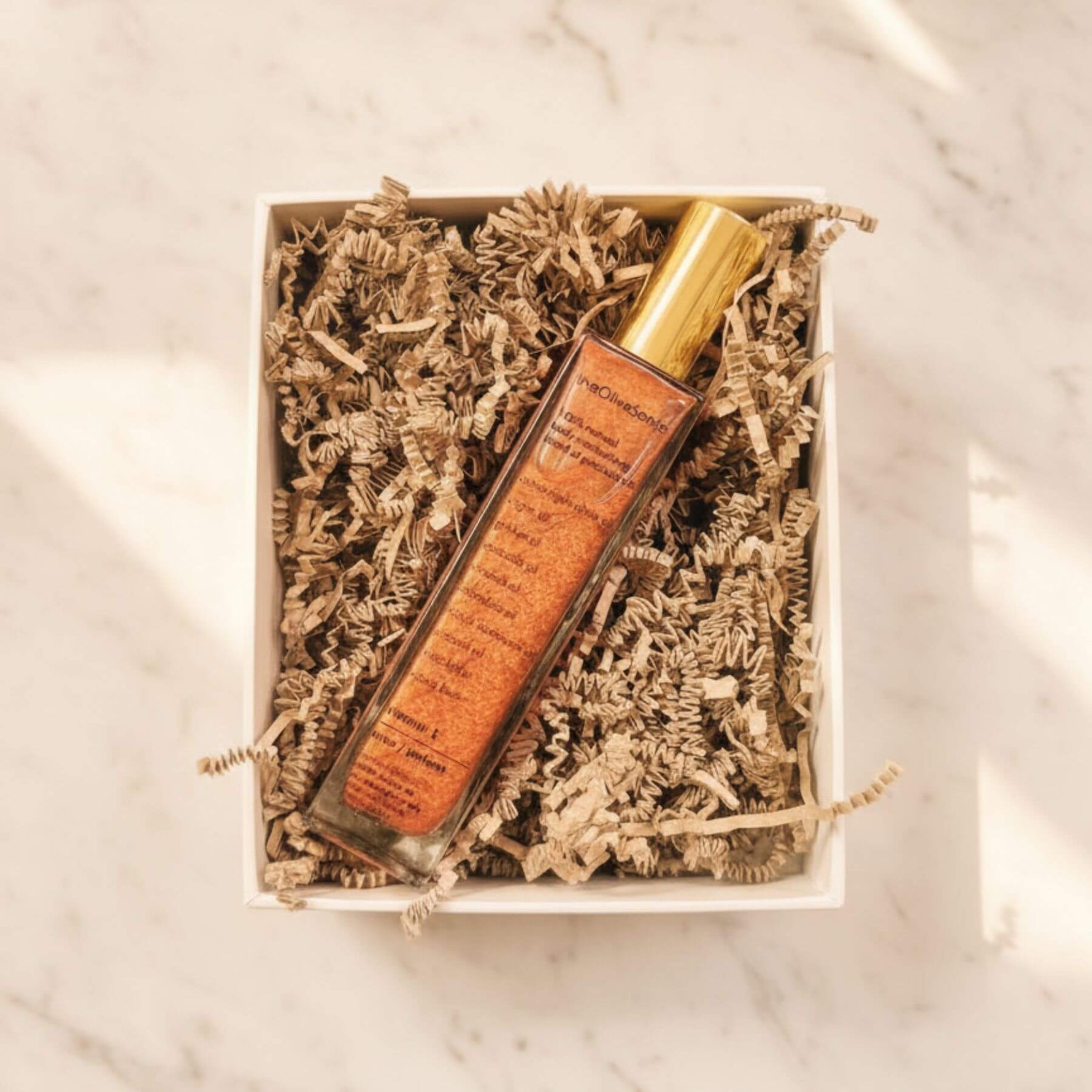 Lip balm in a decorative box with shredded paper on a marble surface