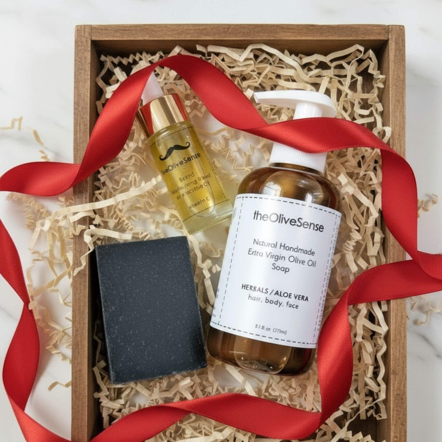 Gift set with olive oil products and a red ribbon in a wooden box.