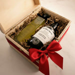 Two bottles of olive oil in a wooden gift box with a red ribbon.