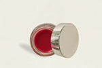 Open cosmetic jar with a metallic lid on a light background