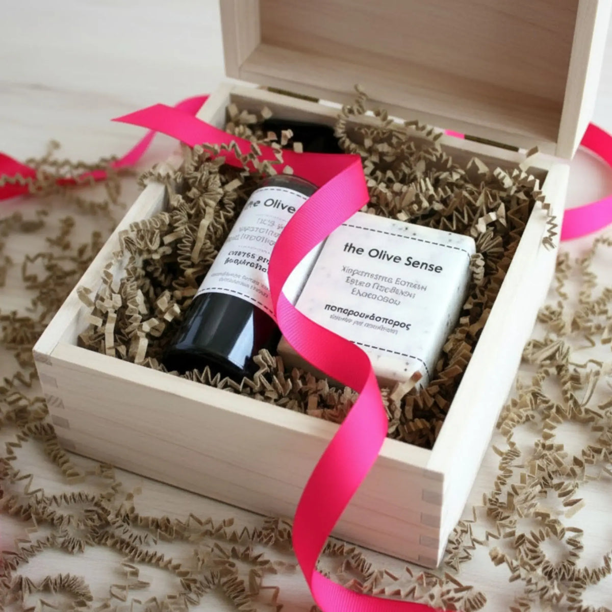 Two bottles of 'the Olive Sense' product in a wooden gift box with a pink ribbon.
