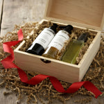 Three skincare bottles in a wooden box with a red ribbon on a rustic wooden surface.