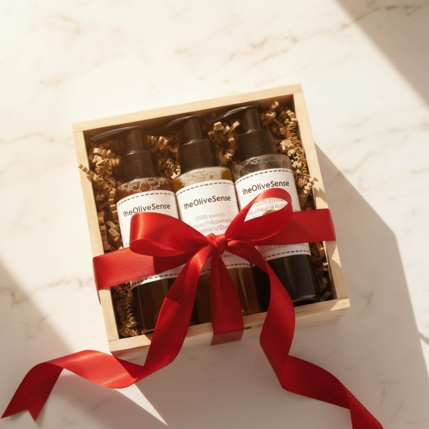 Three bottles of BeOliveSense product in a wooden box with a red ribbon on a light background