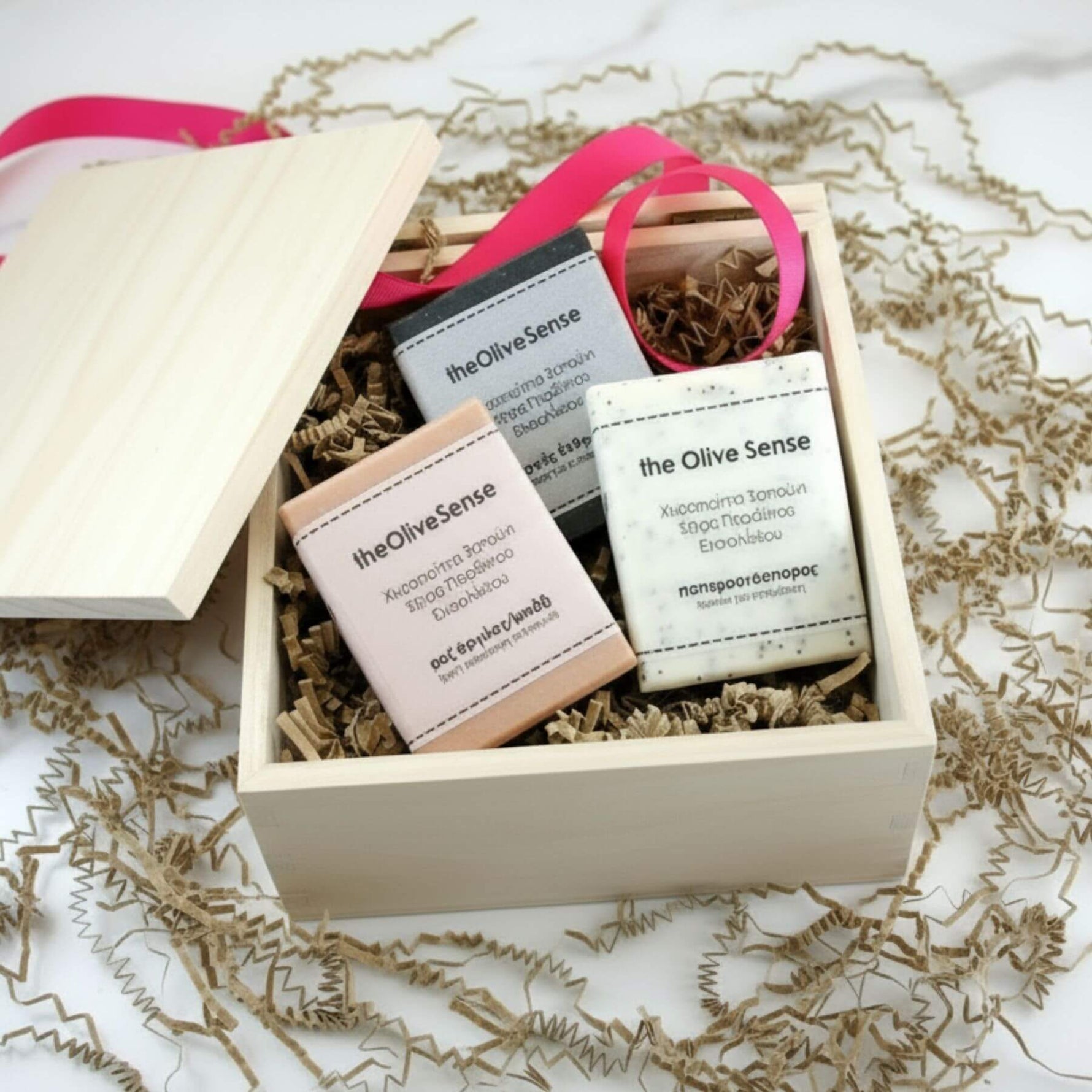 Gift set with 'the Olive Sense' products in a wooden box on a white background.