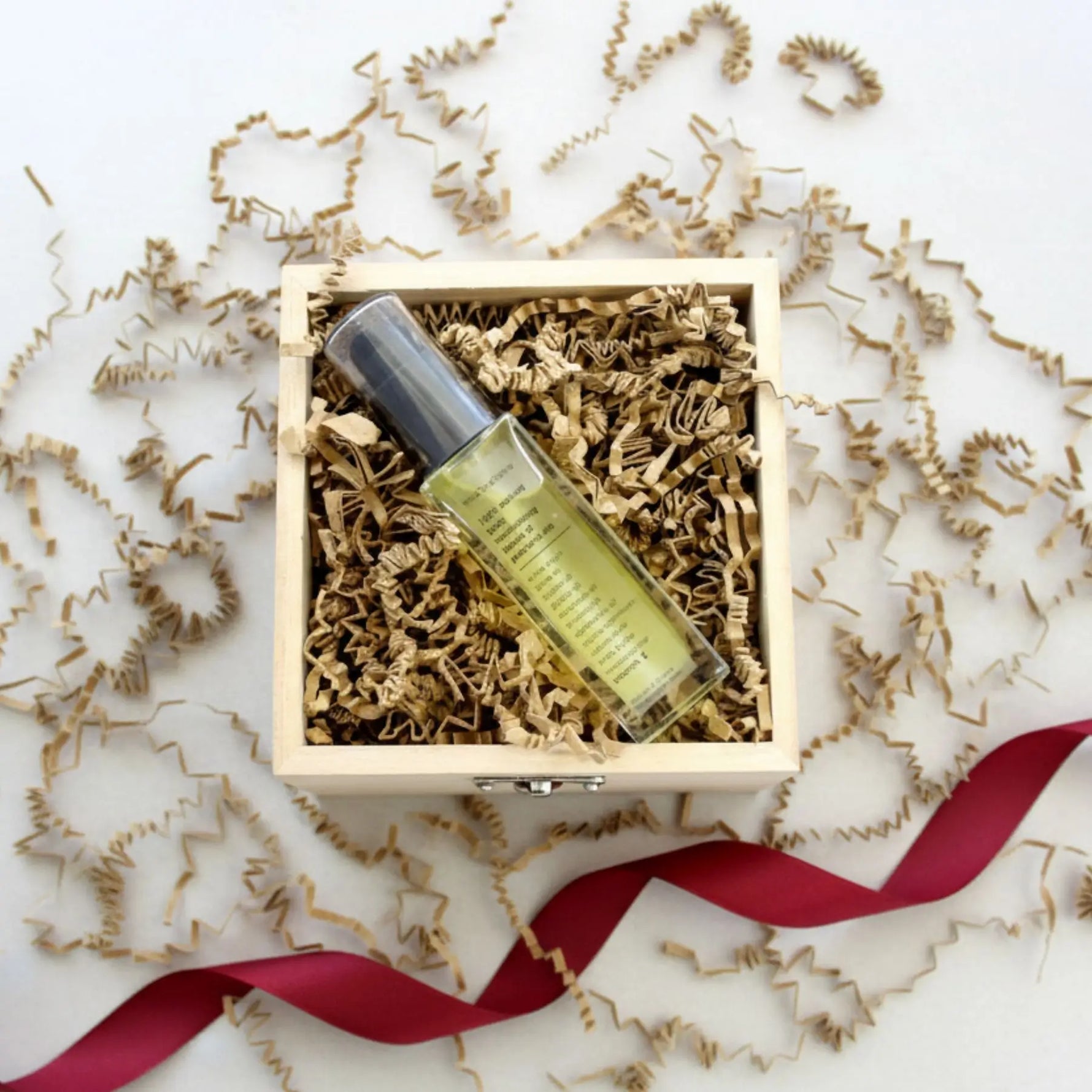Skincare bottle theiOliveSense body oil  a wooden box with decorative paper and ribbon on a light background