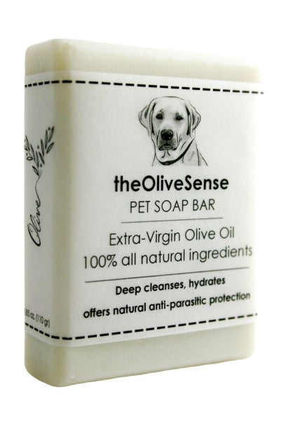 A white bar of pet soap with a label featuring a dog and the text 'The OliveSense Pet Soap Bar, extra virgin olive oil, 100% all natural ingredients, deep cleanses, hydrates, offers natural anti-parasitic protection'.